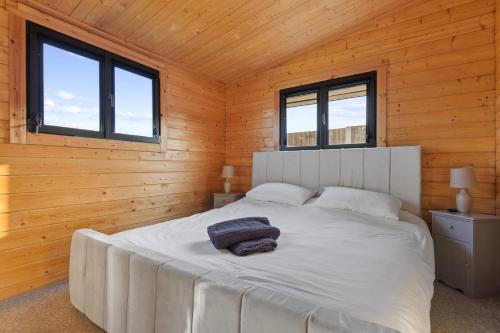 sypialnia z białym łóżkiem w drewnianym pokoju w obiekcie Choller Farm Lodge - Private Hot Tub w mieście Slindon