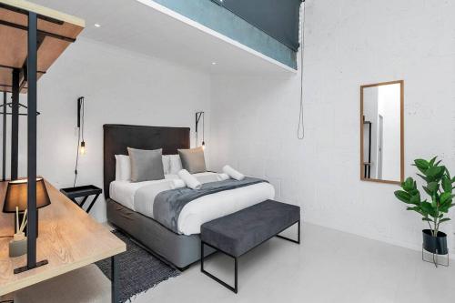 a bedroom with a bed and a table and a mirror at Spice Yard Lofts on Voortrekker-B116 in Cape Town