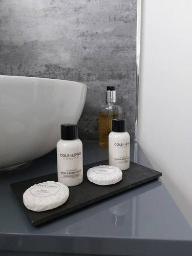 two bottles of soap on a black tray next to a sink at The Woodpeckers - Alresford Essex in Alresford