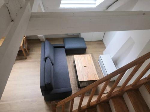 - un salon avec un canapé bleu et une table en bois dans l'établissement Quartier historique de Mantes, au pied de la cathédrale avec vue directe sur celle-ci, à Mantes-la-Jolie