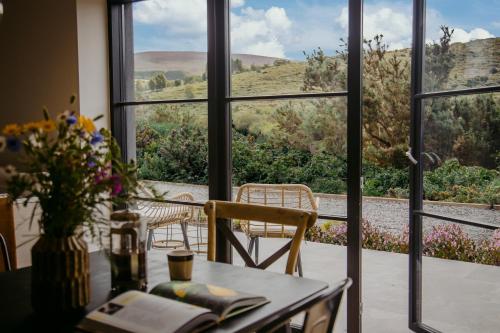 a table with a vase of flowers and a window at The Deerstone Luxury Eco Hideaway in Laragh