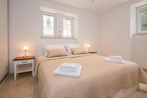a white bedroom with a bed with two towels on it at Superior Apartment CASA SPALATO in Split