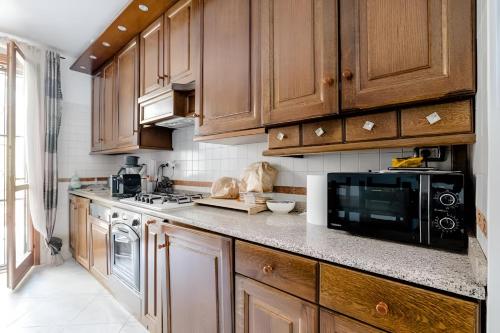 a kitchen with wooden cabinets and a microwave at Garden House Fiera Milano in Pero