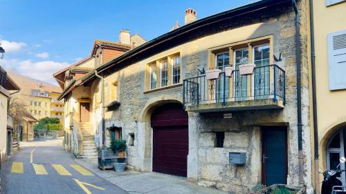un antiguo edificio de piedra con puerta y balcón en Ancienne Maison Vigneronne, en Hauterive