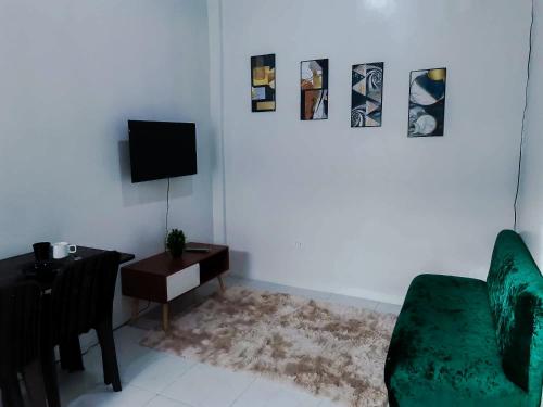 a living room with a green couch and a television at Sleep, Eat, Relax with Serenity in Lucena