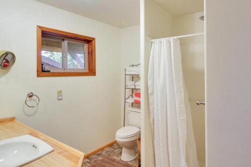 Un baño con inodoro, lavabo y ventana. en Forested Coffman Cove Cabin with Wood-Burning Stove!, en Coffman Cove