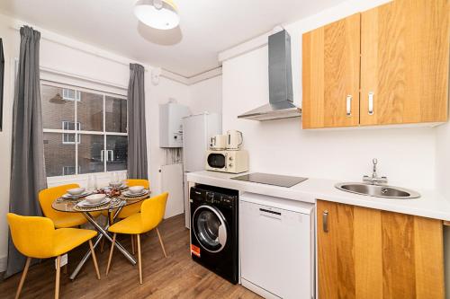 cocina con fregadero y mesa con sillas amarillas en [Covent Garden-Oxford Street] Central London Apartment, en Londres