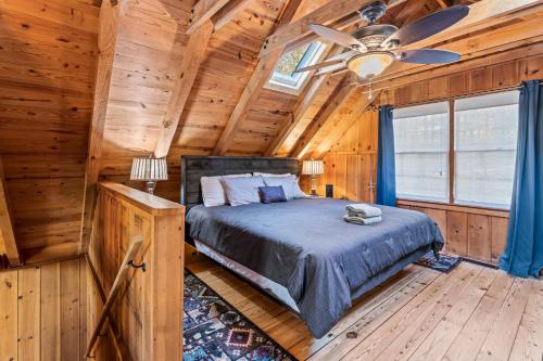 1 dormitorio en una cabaña de madera con 1 cama y ventilador de techo en New Listing! Cabin Fever - Hot Tub, Game Room, 3 King Beds, en Dahlonega
