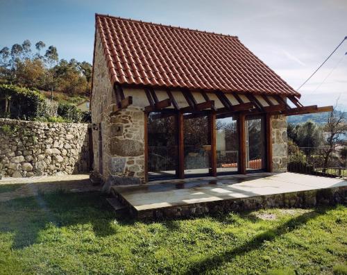 una piccola casa in pietra con tetto su un campo di Casas das Japoneiras a Paredes de Coura
