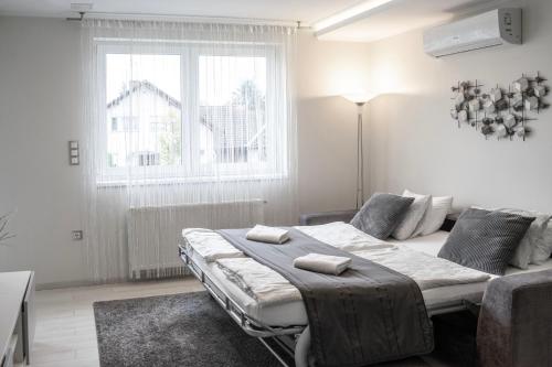 - une chambre avec un lit, un canapé et une fenêtre dans l'établissement Harmony Apartments Sárvár, à Sárvár