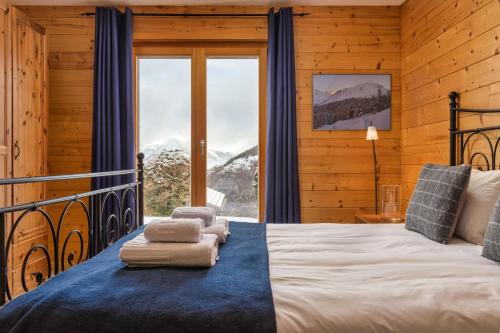 a bedroom with a bed and a large window at Chalet Elbaz - Swiss Chalet with breathtaking views in La Tzoumaz
