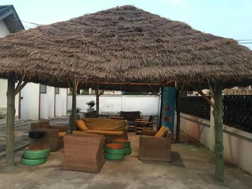 a large straw umbrella with chairs and a couch under it at Nana's Holiday Let in Accra