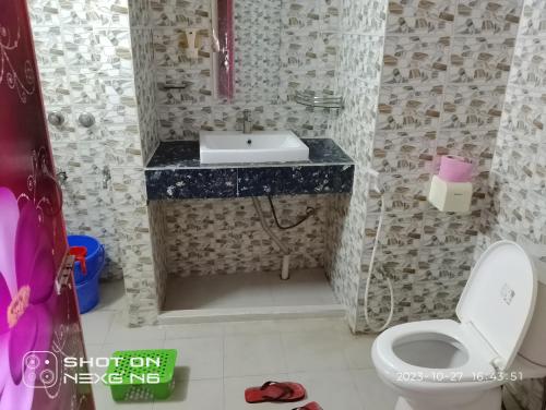 a bathroom with a white toilet and a sink at Coral lagoon resort in Jaliapāra