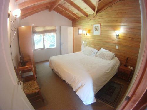 a bedroom with a large white bed in a room at Cabañas Santa Maria Pucon in Pucón