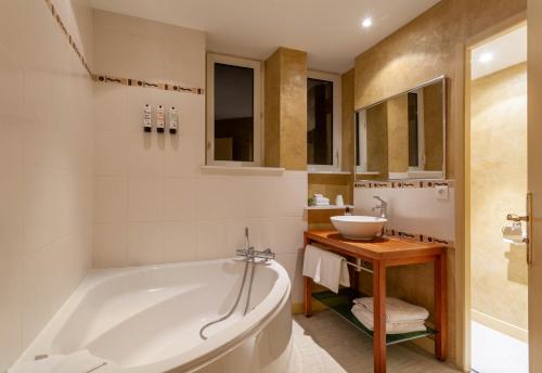 a bathroom with a tub and a sink at Providence Hotel in Vittel