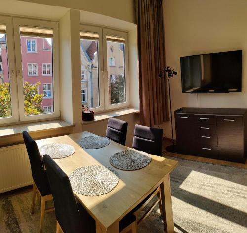 a dining room with a table and chairs and a television at Apartament Gdańsk Starówka in Gdańsk