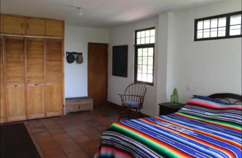 a bedroom with a bed and a chair and windows at Las Mañanitas Habitación Boreal in Medellín
