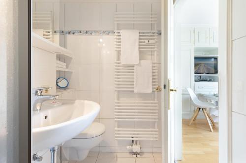 a white bathroom with a sink and a toilet at Dünenperle in List