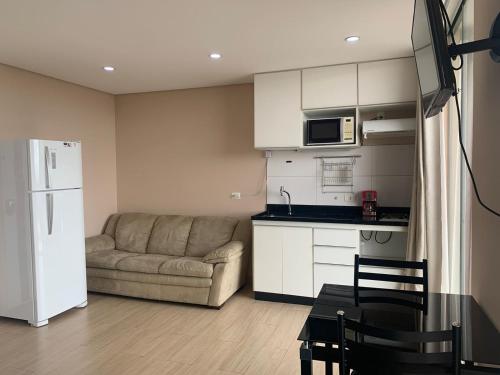 a living room with a couch and a kitchen at Stay GRU - Loft 2 Completo próx GRU airport - Guarulhos in Guarulhos
