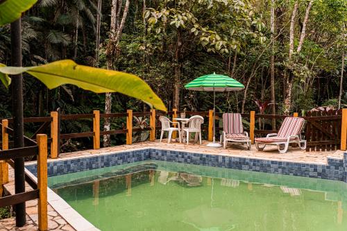 a pool with a table and chairs and an umbrella at Espaço Viverde Penedo in Penedo