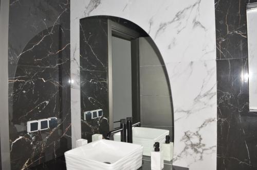 Appartement 5 etoiles agadir vue mer في أغادير: حمام أسود وبيض مع حوض ومرآة