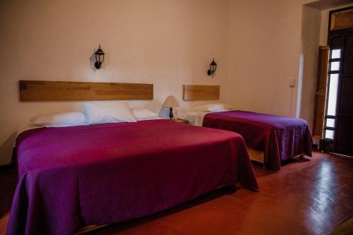 two beds in a room with purple sheets at Hotel Las Golondrinas in Oaxaca City