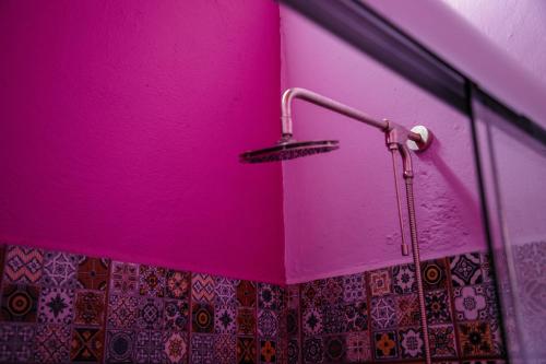 a bathroom with a pink wall and a shower at Hotel Las Golondrinas in Oaxaca City