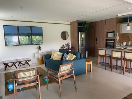 uma sala de estar com um sofá azul e uma cozinha em Pé na areia - Reserva Ecológica - Tranquilidade em Imbassaí