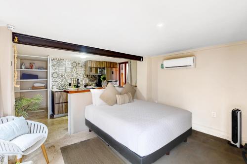 a bedroom with a white bed and a kitchen at Torre Nautilus 1 in Cancún