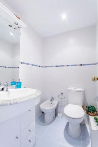 a white bathroom with a toilet and a sink at The Beach Apartment in El Puig