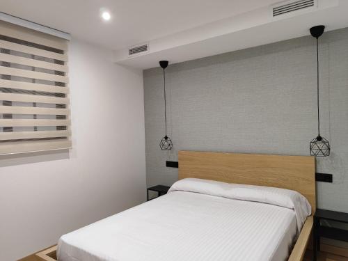 a bedroom with a bed and two pendant lights at Fernando Quero 21 in Andújar