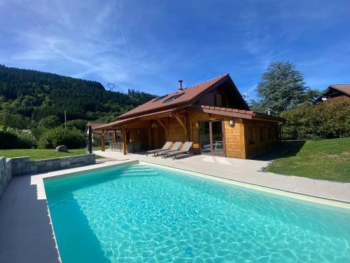 a house with a swimming pool in front of a building at Gîte Chalet avec bain nordique et piscine 11 pers Hautes Vosges in Plainfaing