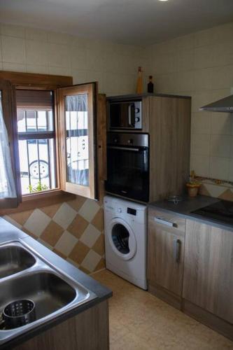 a kitchen with a sink and a washing machine at La casa de la Golondrina in Pedro Bernardo