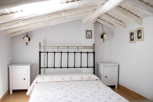 a bedroom with a bed with white walls and wooden floors at La casa de la Golondrina in Pedro Bernardo