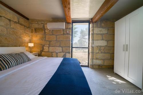a bedroom with a bed and a stone wall at Lunzjata Maisonette in Victoria