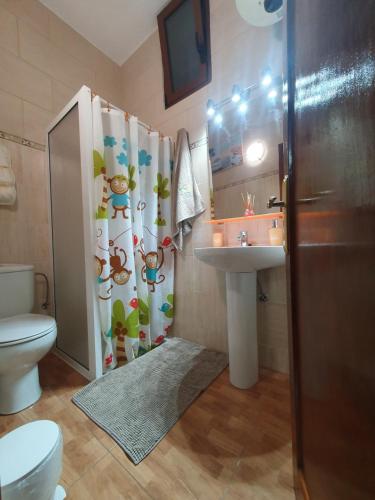 a bathroom with a toilet and a sink and a shower curtain at Casa Cueva Paquito in Vega de San Mateo
