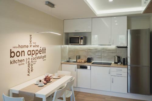 a kitchen with white cabinets and a table and a refrigerator at Harmony Apartments Sárvár in Sárvár