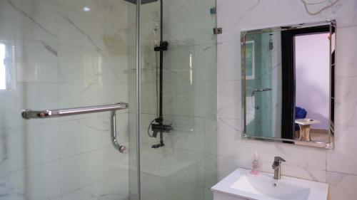 a bathroom with a shower with a sink and a mirror at BOL LODGE AND APARTMENT in Lagos