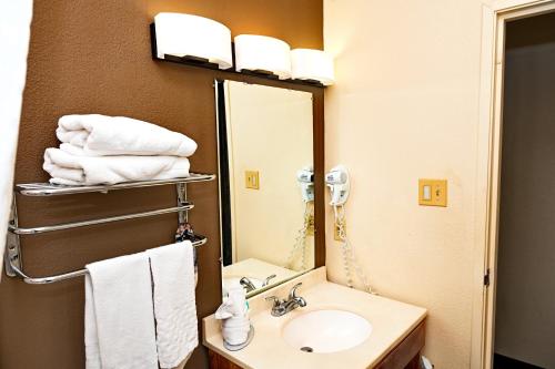 a bathroom with a sink and a mirror and towels at Savai Hotel in Overland Park
