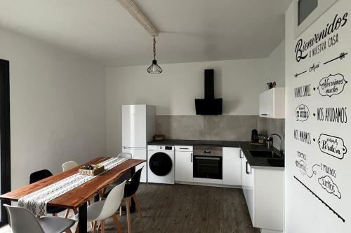 cocina con mesa de madera y cocina con electrodomésticos blancos en Apartamento A Cachola, en Cangas de Morrazo