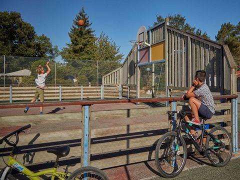 un homme assis sur une clôture à côté d'un garçon sur un vélo dans l'établissement Mobil home SGB, à La Boissière-de-Montaigu