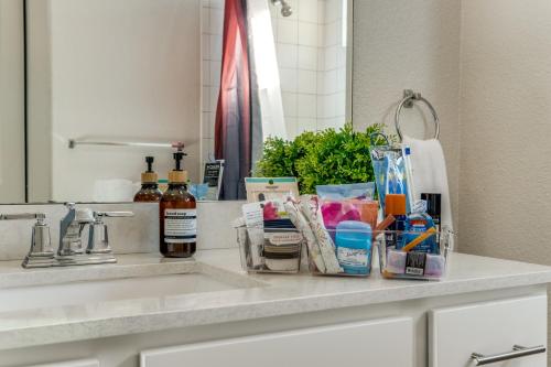 un mostrador de baño con lavabo con artículos de higiene en Radiant condo on the Riverwalk 1325, en San Antonio