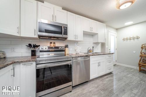 a white kitchen with a stove and a microwave at BoHo Chic Suite - Long Stays - Fireplace - Garage in Edmonton
