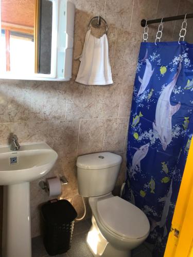y baño con aseo, lavamanos y cortina de ducha. en Reserva Natural Finca La Cabaña, en Dosquebradas