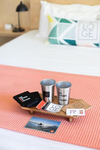 a tray with two coffee cups on a bed at LOGE Westport in Westport