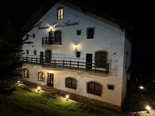 a large white building with a balcony at night at Pensiunea Casa Ancutei in Ranca