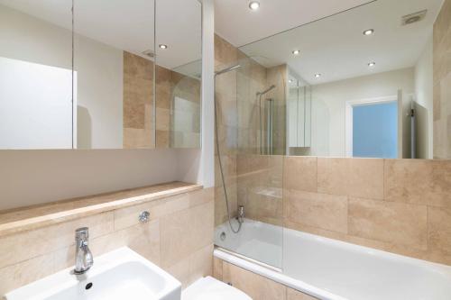 a bathroom with a sink and a tub and a mirror at Renovu Premium Homes in Kensington in London