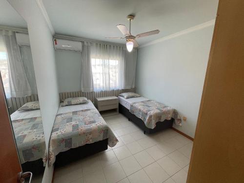 1 dormitorio con 2 camas y ventilador de techo en Res Palmeiras, en Bombinhas