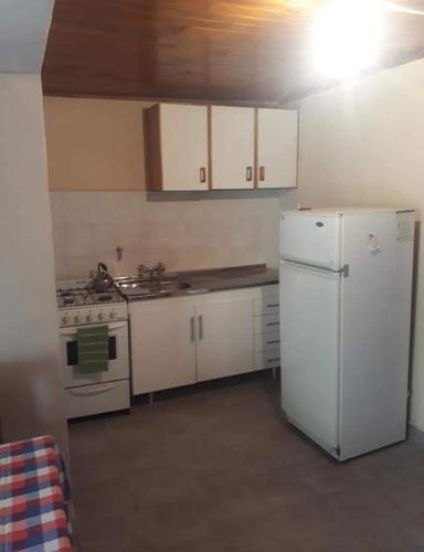 La cuisine est équipée de placards blancs et d'un réfrigérateur blanc. dans l'établissement Departamentos Carhue, à Carhué