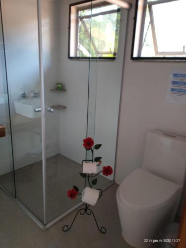 a bathroom with a shower and a toilet and red roses at Espaço Viverde Penedo in Penedo